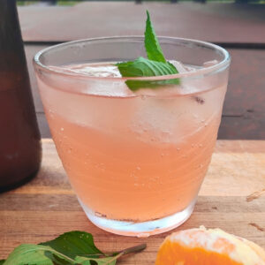 Mimosa flower soda on ice in a serving glass with mint sprig