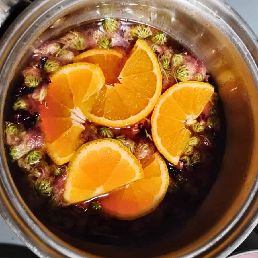 pot with mimosa flowers in syrup and topped with orange slices. 