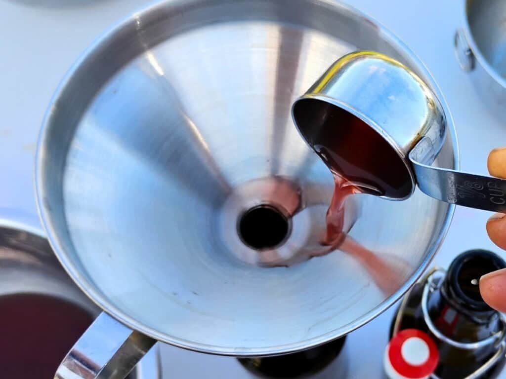adding syrup to a bottle through a funnel
