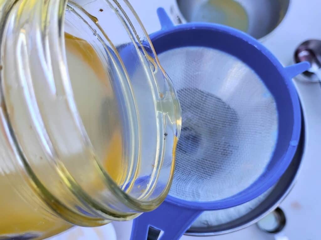 adding water kefir to bottles through a strainer.